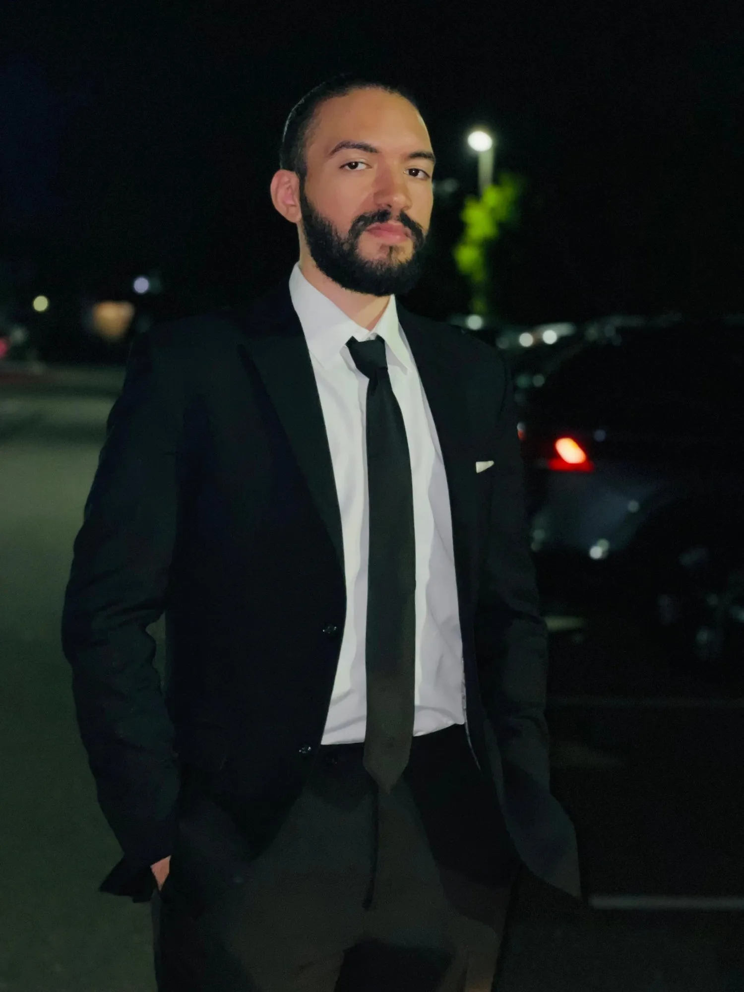 Nour Mohsen in a black suit, outdoors at night